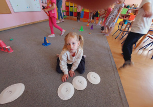 Dziewczynka na dywanie układa nymer alarmowy 998.