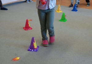 Dziewczynka w strażackim kasku przechodzi pomiędzy przeszkodami.