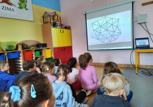 Dzieci siedzą przed ekranem.