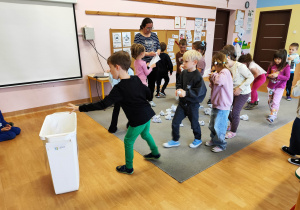 Chłopiec wrzuca śmieci do kosza.