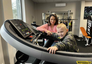 Mały chłopiec ćwiczy na bieżni.