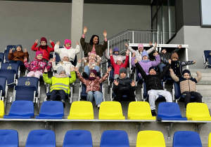 Dzieci siedzą na trybunach bioska sportowego.