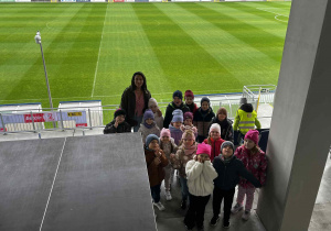 Przedszkolaki na boisku sportowym pozują do zdjęcia.