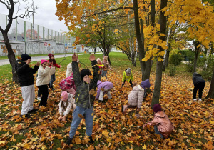 Dzieci bawią na łące bawią się kolorowymi liśćmi.