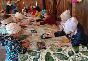 Przedszkolaki malują farbami.