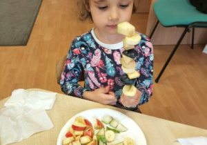 Dziewczynka trzyma owocowy szaszłyk.