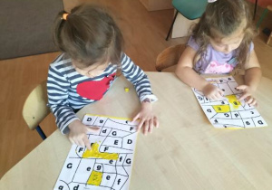 Dziewczynki przy stoliku wykonują kartę pracy.