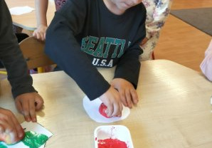 Chłopiec odciska stempel z jabłka na kartonie.