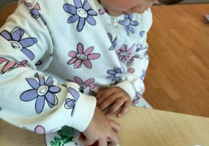 Mała dziewczynka stempluje kartonową sylwetę słoika.