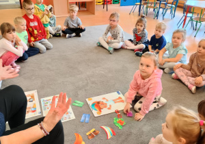 Dziewczynka trzyma sylwetę papierowego ubrania.
