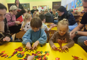 Dzieci z rodzicami wyklejają drzewka.