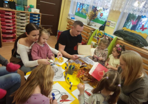 Dzieci z rodzicami wyklejają dynie.