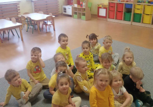 Dzieci siedzą na dywanie.