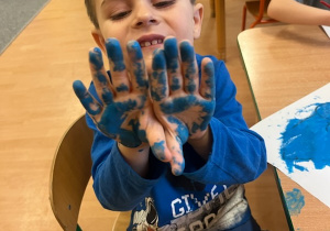 Chłopiec z pomalowanymi niebieską farbą rękoma.