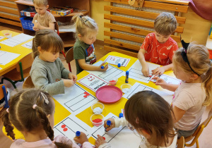 Dzieci wyklejaja flagę.