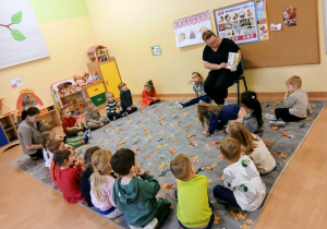 Dzieci siedzą na dywanie.