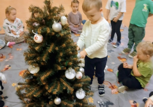 Chłopiec ozdabia choinkę.