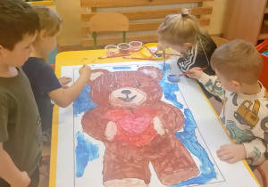 Wspólna praca -miś. Dzieci maluja farbami.
