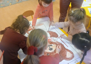 Dzieci kolorują misia farbami.