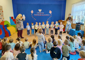 Dzieci stoją z książkami w rękach.