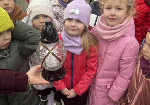Grupa przedszkolaków patrzy na znicz.
