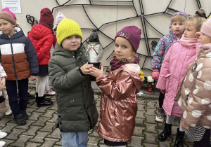 Chłopiec z dziewczynką trzymają znicz.