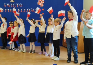 Dzieci machają biało - czerwonymi flagami.