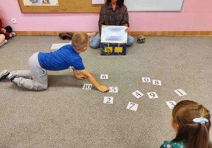 Chłopiec wskazuje na szablon przedstawiający cyfrę 5.