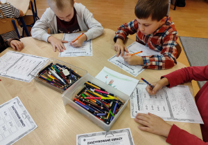 Dzieci siedzą przy stoloikach i rozwiązują zadania matematyczne.