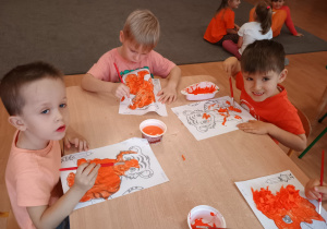 Małe dzieci malują farbami.