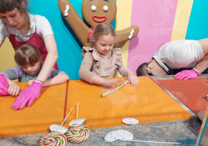 Dziewczynki z masy karmelowej robią kolorowe lizaki.