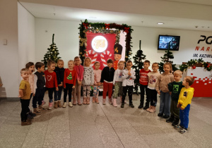 Przedszkolaki pozują do zdjęcia na tle świątecznych dekoracji.