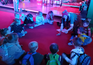 Grupa dzieci siedzi na dywanie i słucha Elfa.