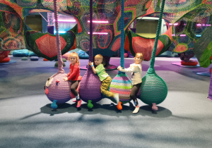 Dzieci huśtają się na huśtawce w kształcie gąsiennicy.