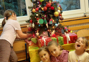 Dziewczynki siedzą przy choince.