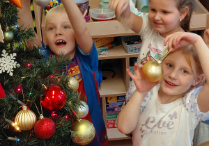 Dzieci trzymają choinkowe ozdoby.