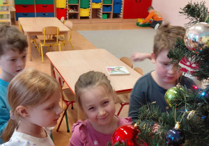 Przedszkolaki dekorują choinkę.