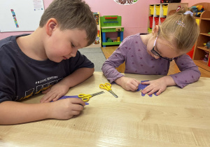 Dzieci ozdabiają sylwetę dłoni, wyciętą z papieru.