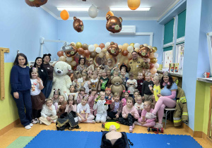 Przdszkolaki z misiami pozują do zdjęcia.