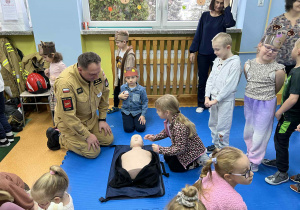 Dziewczynka uczy się udzielania pierwszej pomocy z użycie fantoma.