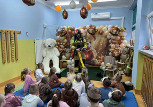 Dzieci ogladają strój ochronny strażaka.