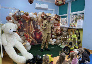Przedszkolaki słuchają prelekcji strażaka.