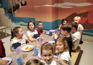 Przedszkolaki spożywają posiłek przy stole.