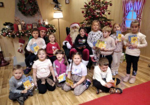Dzieci pozują do zdjęcia z Mikołajem.