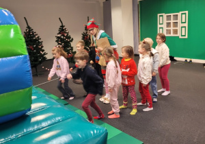 Dzieci w kolejce stoją przed nadmuchiwaną zjeżdżalnią.