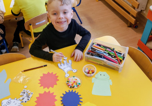 Chłopiec siedzi i koloruje wirusa.