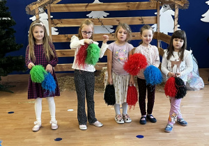 Dzieci trzymają pompony w ręku.