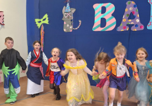 Dzieci tańcząc trzymają się za ręce.