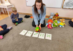 Kobieta z pacynką siedzi na dywanie.