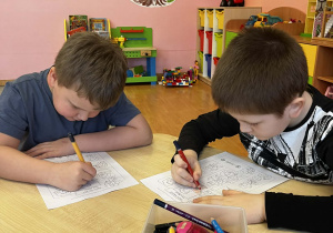 Chłopcy przy stoliku wykonują kartę pracy.